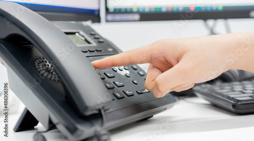 Foto close up employee man hand pointing try to press button number on telephone offi
