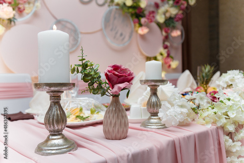 Decorated pink wedding presidium, festive arch, screen for just married, event organization. Beautiful flowers, leaves, candles. Close up