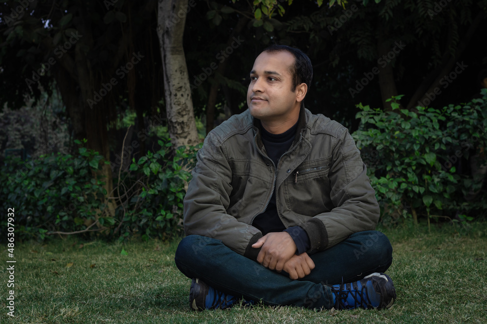 young man different moods of expression cross leg sitting in a park from flat angle young man different moods of expression cross leg sitting in a park from flat angle