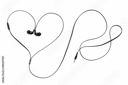 Ear plugs for music lovers in the shape of a heart. Earphones headset on a white background. Vacuum wired black headphones for listening music and sound on portable devices. In-ear headphones.