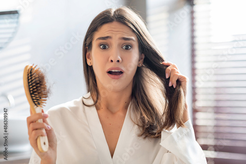 Schilderij op canvas Shocked Young Woman Worried About Hairloss After Brushing Hair In Bathroom