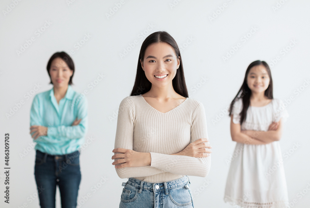 Young Asian woman with mature mother and cute daughter posing with crossed arms and smiling on white background Young Asian woman with mature mother and cute daughter posing with crossed arms and smiling on white background