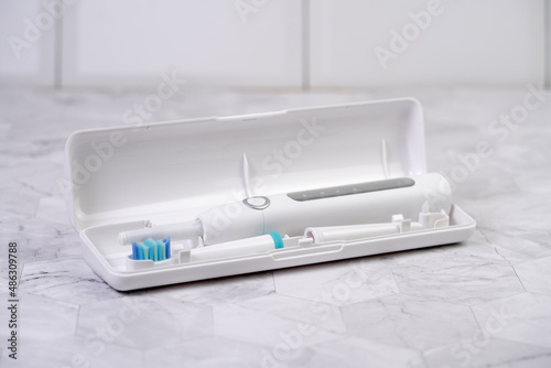 Modern white sonic or electric toothbrush in travel case. Concept of professional oral care and healthy teeth by using sonic smart toothbrush. Minimal design © Zkolra