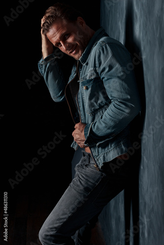 handsome sexy male model alone in the studio, a man with beautiful athletic muscles, jeans and a white t-shirt
