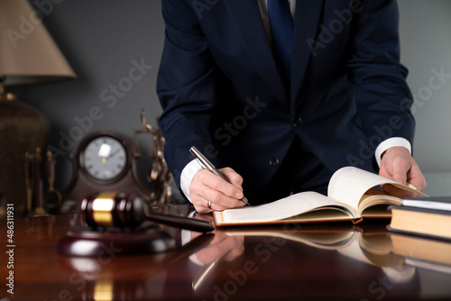 Judge working at the office. Mallet  Themis statue  scale and documents on the brown shining table.