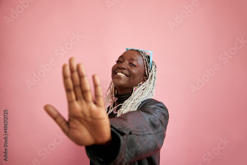 Studio portrait of smiling woman with bleached braided hair showing stop gesture photo
