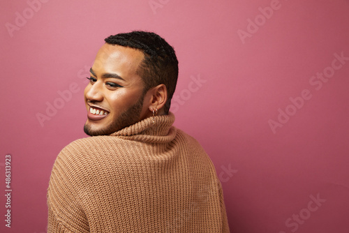 Studio portrait of smiling queer man against purple background
