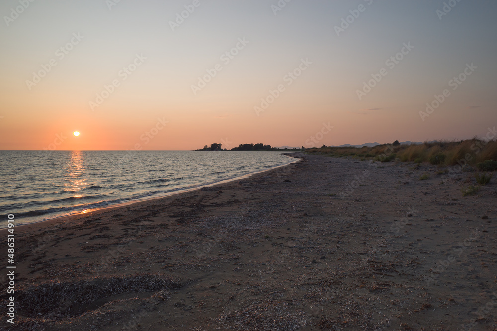 Sunset over Ionian Sea, twilight on wild beach near island of Lefkada, Greece