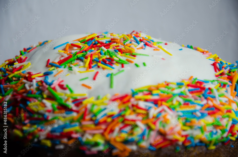 Traditional Easter cake decorated with icing and multicolored decor. Traditional sweets for the Christian holiday. Festive background with copy space.