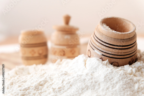 Flour scattered on the table in beautiful wooden dishes, pots. Close-up. The concept of harvest, flour products, grain crops.