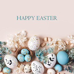Easter eggs with sweets and flowers on beige. Happy Easter concept. White and blue eggs and cute nest with candy