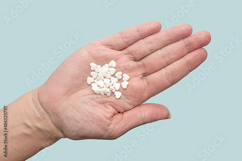 Medicines in the shape of a heart lie on the palm of your hand. On a blue background.