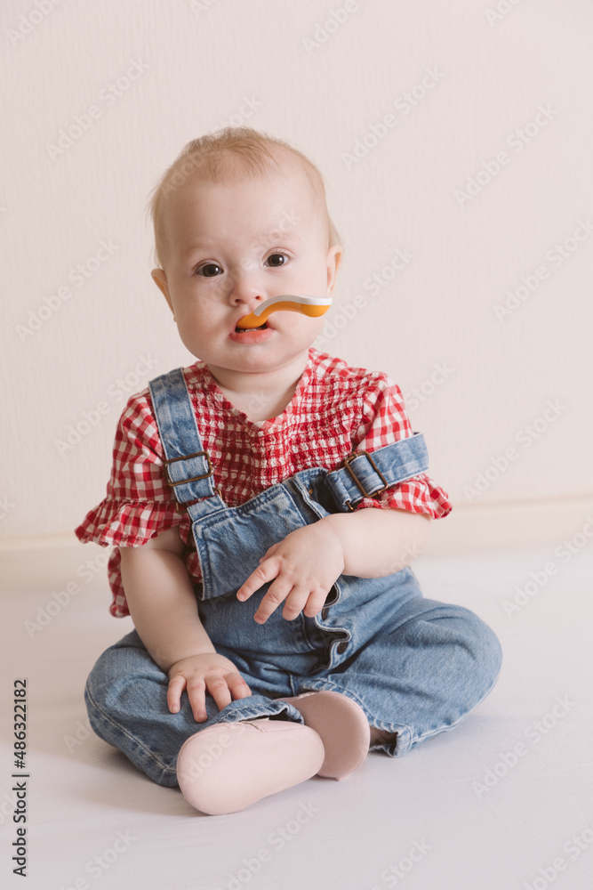 Portrait of cute baby with a spoon in overall jeans and a red plaid shirt. Portrait of cute baby with a spoon in overall jeans and a red plaid shirt.