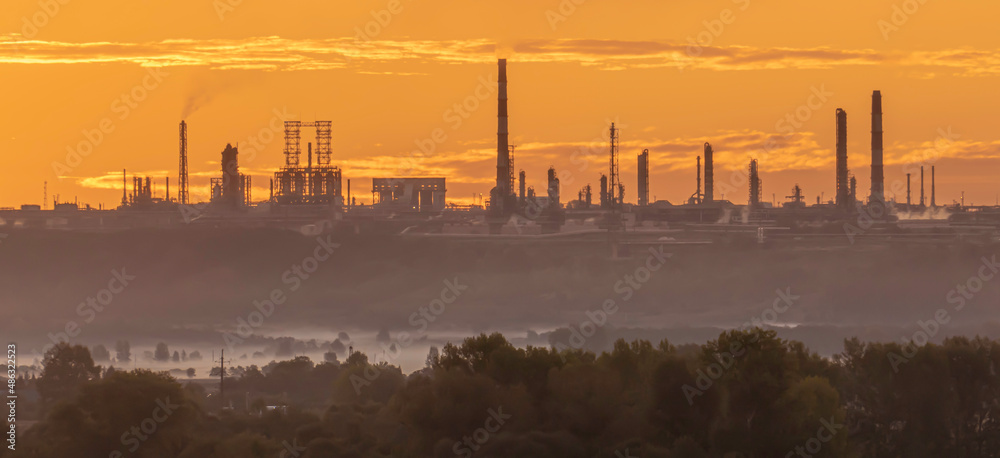 Fototapeta premium Industrial landscape with silhouettes of factory chimneys at dawn