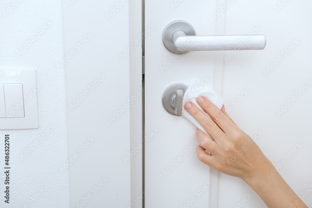 Cleaning door handles with an antiseptic wet wipe and gloves. Sanitize surfaces prevention in hospital and public spaces against corona virus. Woman hand using towel for cleaning home room door link. Cleaning door handles with an antiseptic wet wipe and gloves. Sanitize surfaces prevention in hospital and public spaces against corona virus. Woman hand using towel for cleaning home room door link.