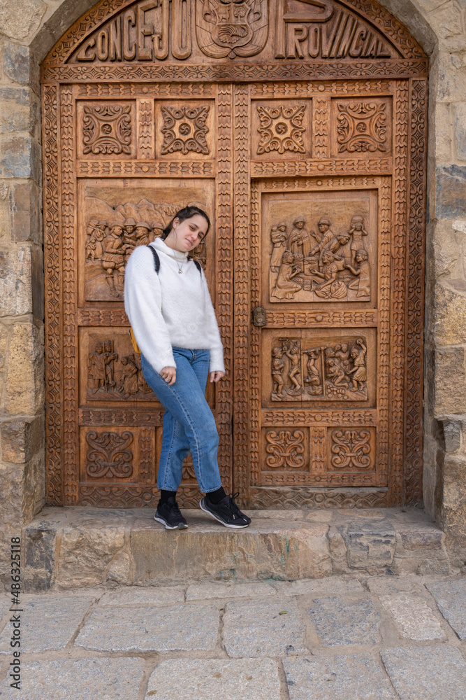 Young woman posing in front of an ornated wooden door