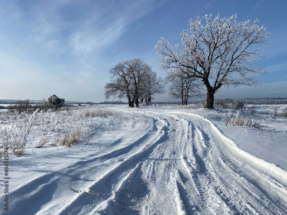 Winter dirt road along the forest. Winter landscape.