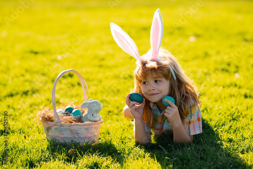 Easter bunny children. Kids boy in bunny ears hunting easter eggs in park outdoor.