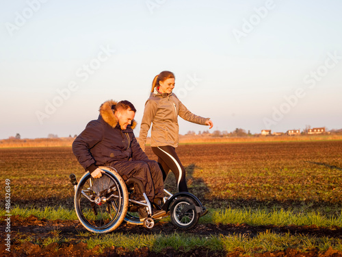 Smiling woman and man on wheelchair in field