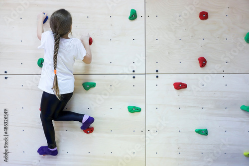 rock climbing training takes place regularly in the children's rehabilitation center for children with diseases and developmental disabilities. girl in a white shirt and a long pigtail