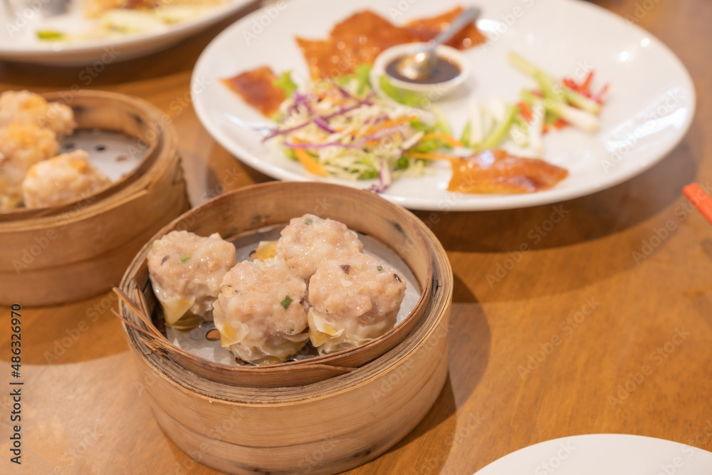 Kanom Jeeb or Steamed Pork and Shrimp Dumplings in a bamboo steamer. Shumai is a chinese cuisine dish with minced pork meat, shrimps, and vegetables. Chinese food