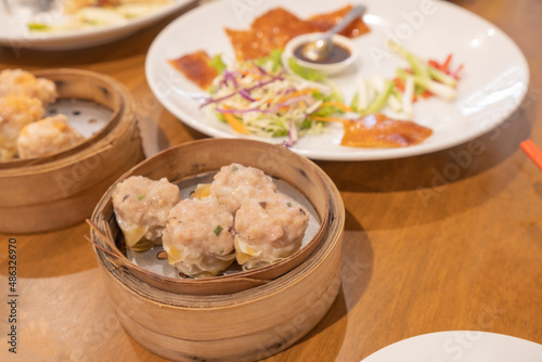 Kanom Jeeb or Steamed Pork and Shrimp Dumplings in a bamboo steamer. Shumai is a chinese cuisine dish with minced pork meat, shrimps, and vegetables. Chinese food photo