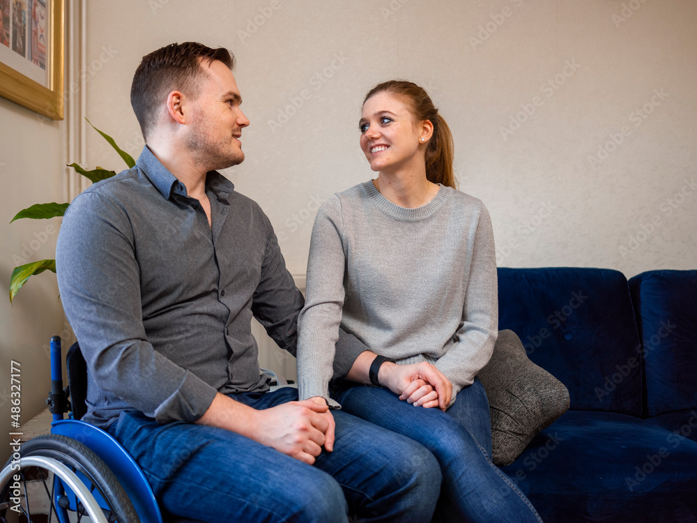 Smiling woman and man on wheelchair at home