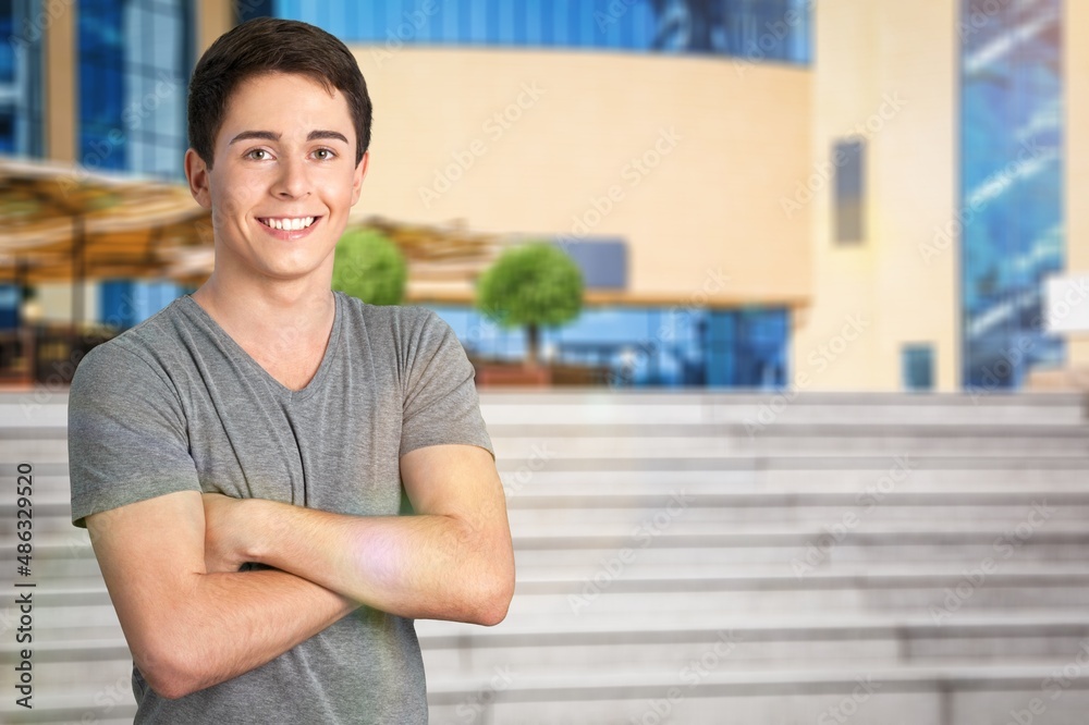 Fototapeta premium Cheerful Guy Smiling To Camera Posing Crossing Hands Standing Over Background.