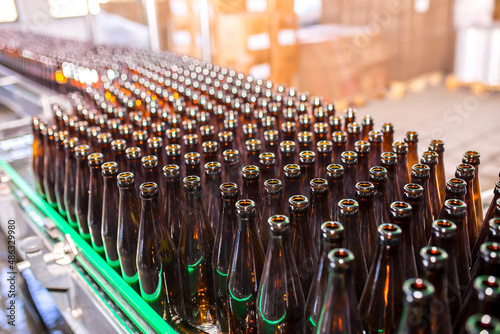 Brewery factory spilling beer into glass bottles on conveyor lines. Industrial work  automated production of food and drinks. Glass products. Bottles for drinks. Technological work at the factory.