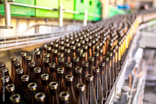 Brewery factory spilling beer into glass bottles on conveyor lines. Industrial work  automated production of food and drinks. Glass products. Bottles for drinks. Technological work at the factory.