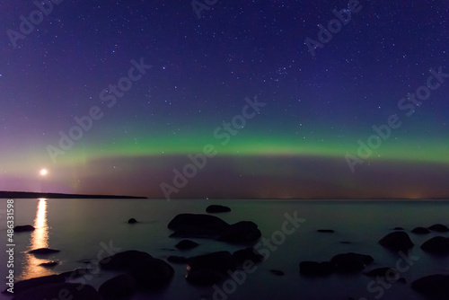 Arcuate aurora green above the lake with moon