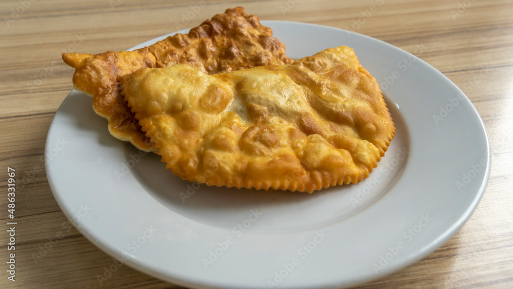 Homemade pasties with meat filling on white plate. traditional Caucasian and Russian cuisine. Take away food concepts Homemade pasties with meat filling on white plate. traditional Caucasian and Russian cuisine. Take away food concepts