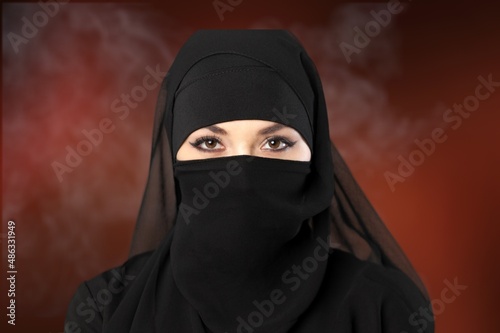 Portrait of young woman in black burqa with hidden face, photo