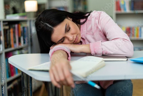 Caucasian tired woman sleeping around stack of papers and books at the table after working and studying. Work and study concept photo