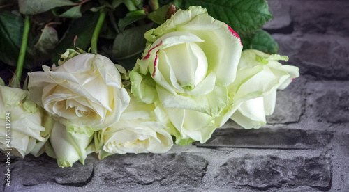 A beautiful bouquet of white roses on a background of stone paving stones. A bouquet of flowers illuminated by soft light.