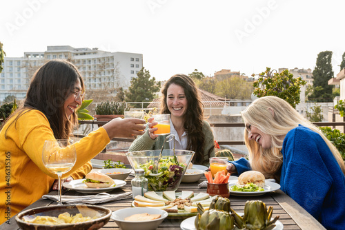 Happy friends having fun drinking and eating vegan food outdoor - Focus on right girl face