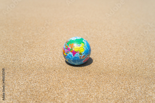 Toy globe on the sand of beach. World travel concept.