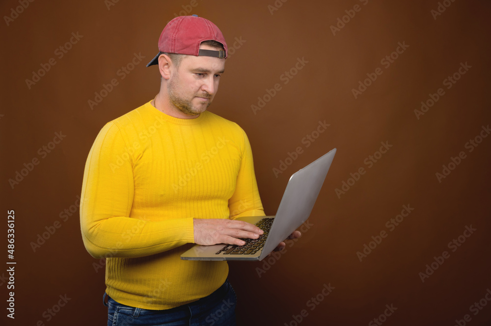 A man uses a laptop in the studio. Chubby man with his laptop stands in the studio A man uses a laptop in the studio. Chubby man with his laptop stands in the studio