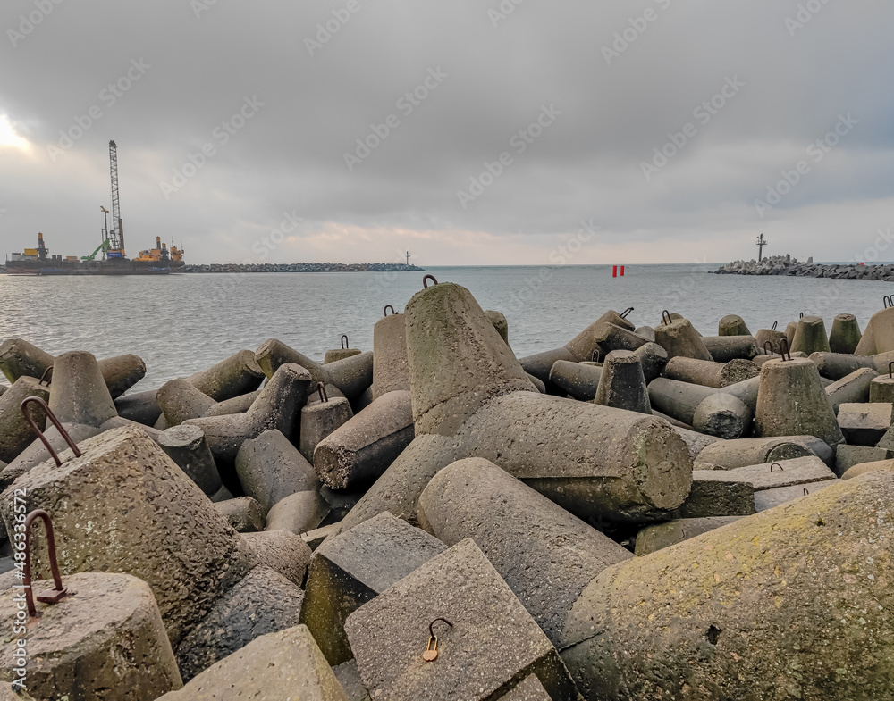 Photo of an artificial stone breakwater in the port at the sea gate in Baltic sea, Klaipeda Photo of an artificial stone breakwater in the port at the sea gate in Baltic sea, Klaipeda