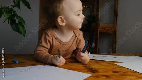 Adorable caucasian toddler boy with felt-tip pens denies something shakes his head. First baby drawings, disagreement, childish caprices concept.  photo