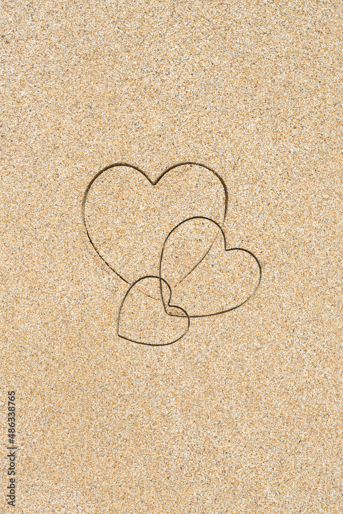 Fototapeta premium Hand-drawn shape of three heart on sand tropical beach. valentines day. Holiday, the vacation of family, friends concept. Creative, background, copy space, travel, summer. Flat lay