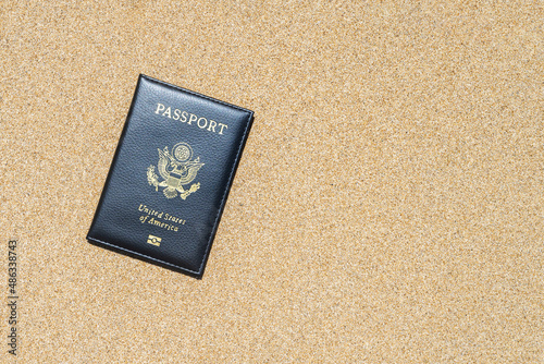 American passport in a cover lying on the sand of the beach. Concept of summer travel, tourism, holiday, vacation.