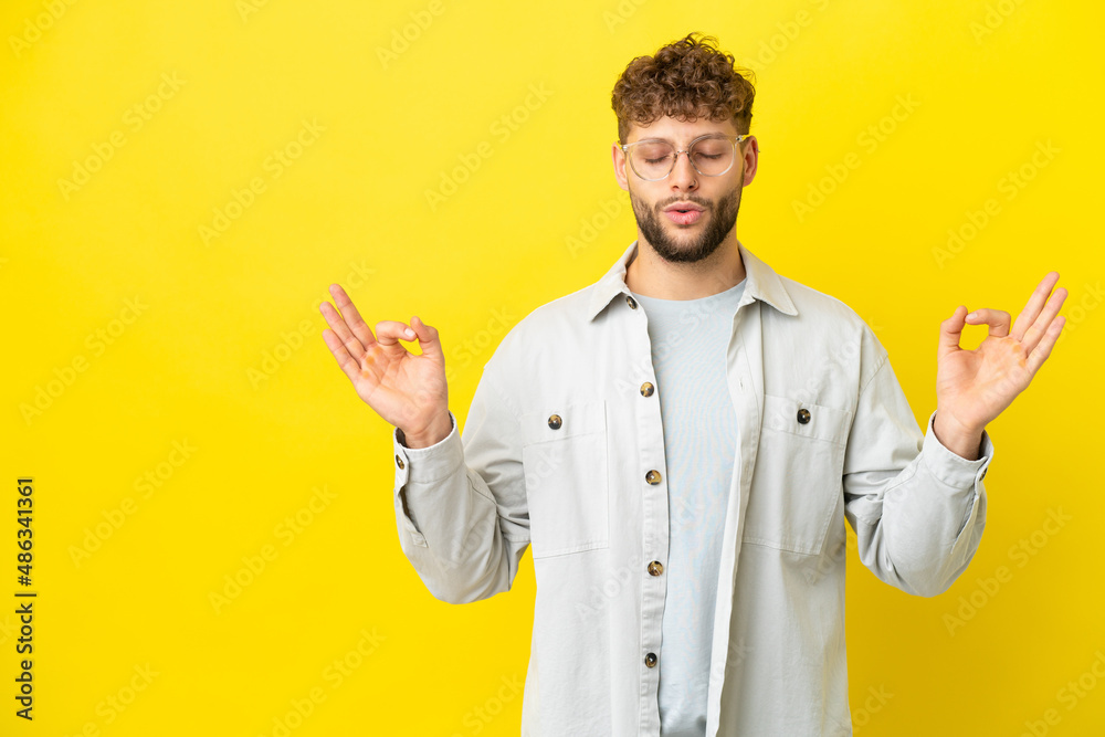 Young handsome caucasian man isolated on yellow background in zen pose