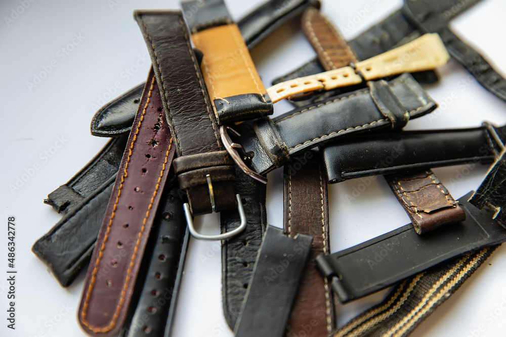 Old worn leather watch bracelets with a clasp in a pile. Old worn leather watch bracelets with a clasp in a pile.