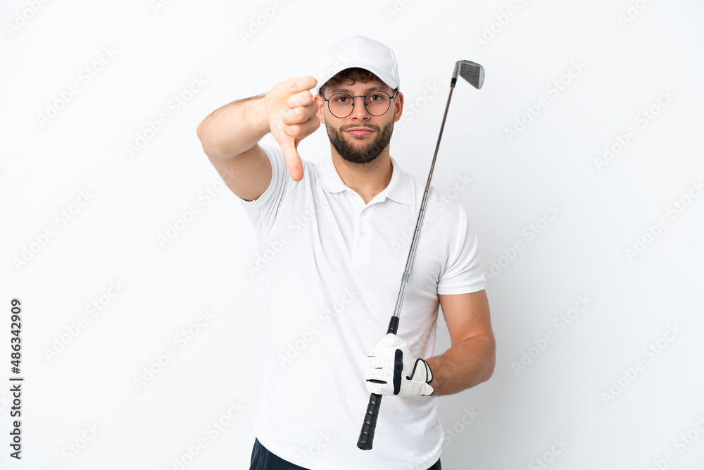 Handsome young man playing golf isolated on white background showing thumb down with negative expression Handsome young man playing golf isolated on white background showing thumb down with negative expression