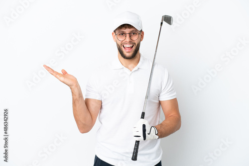 Handsome young man playing golf isolated on white background with shocked facial expression