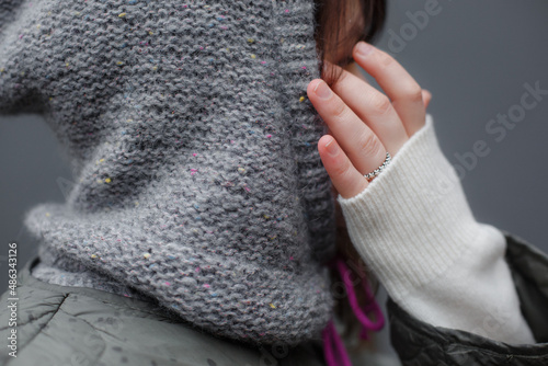 Close-up shot of a knitted woolen hood. Gray handmade alpaca sweater