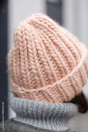 handmade hat in soft pastel peach color. A handmade woolen hat is coolly removed. Hipster girl in the cold season