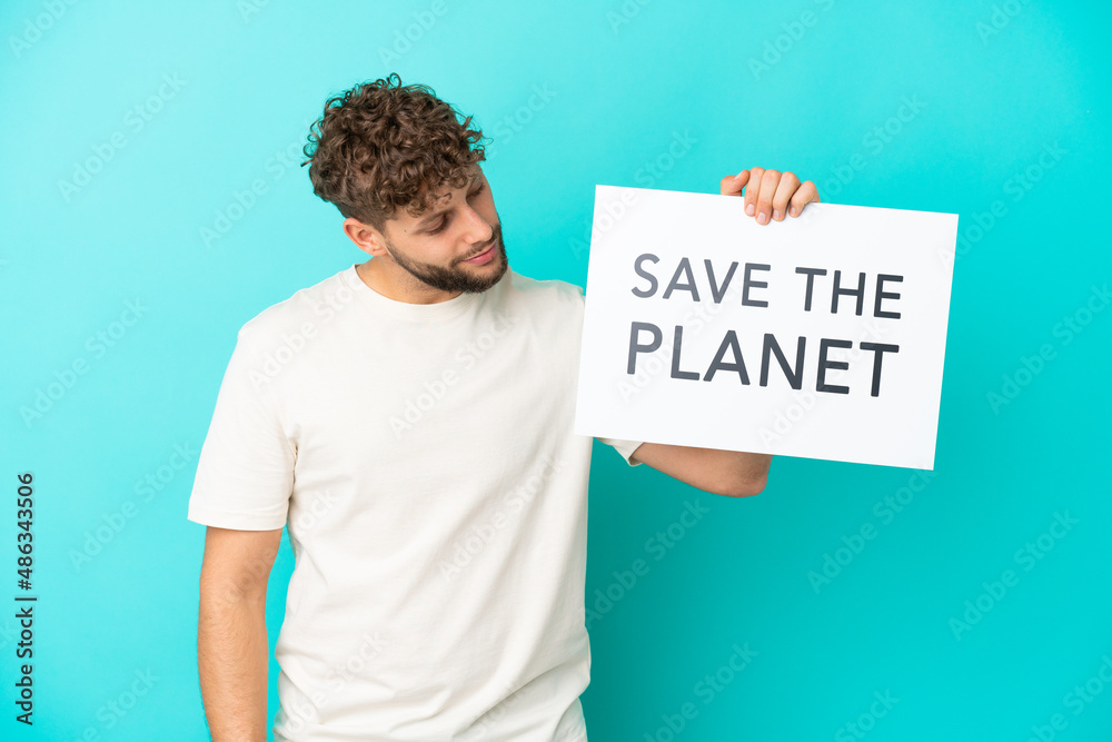 Young handsome caucasian man isolated on blue background holding a placard with text Save the Planet Young handsome caucasian man isolated on blue background holding a placard with text Save the Planet