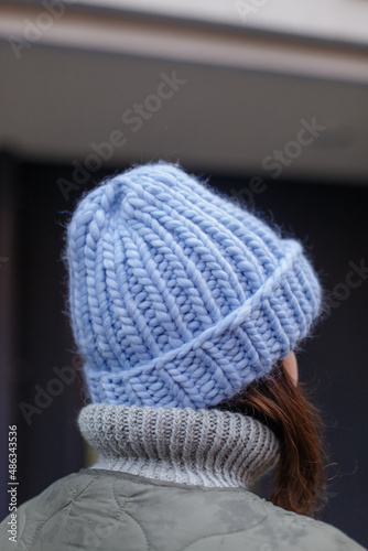  A handmade hat of very berry color on a girl s head. The girl straightens a fashionable woolen hat with her hands on her head